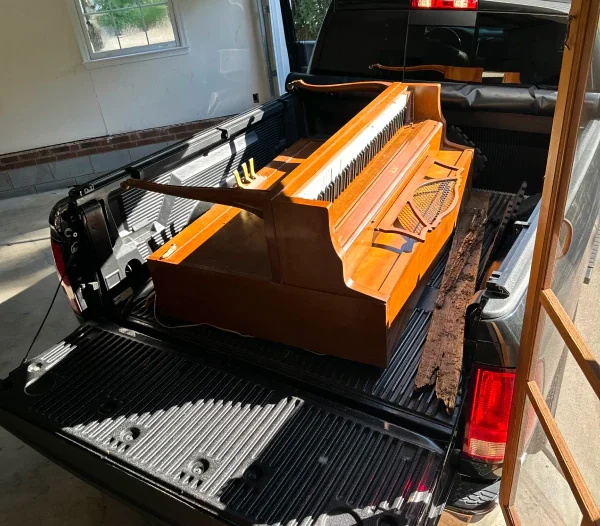 old piano loaded on a back of pickup truck